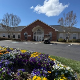 a clubhouse with parking and landscaping in front of it